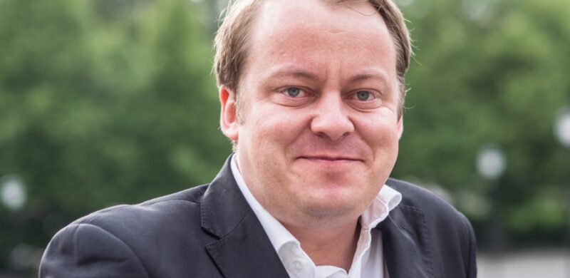 Erlend Wiborg. Portrett. Grønne trær i bakgrunnen. Foto. Erlend Wiborg. Portrett. Grønne trær i bakgrunnen. Foto.