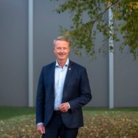 Terje Søviknes smilende foran tre i høstfarger. Foto