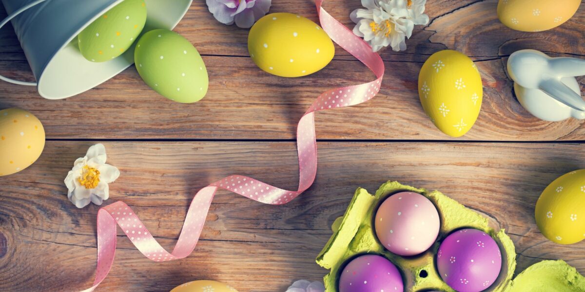 Fargerike egg og blomster på et bord laget av treverk. Foto.