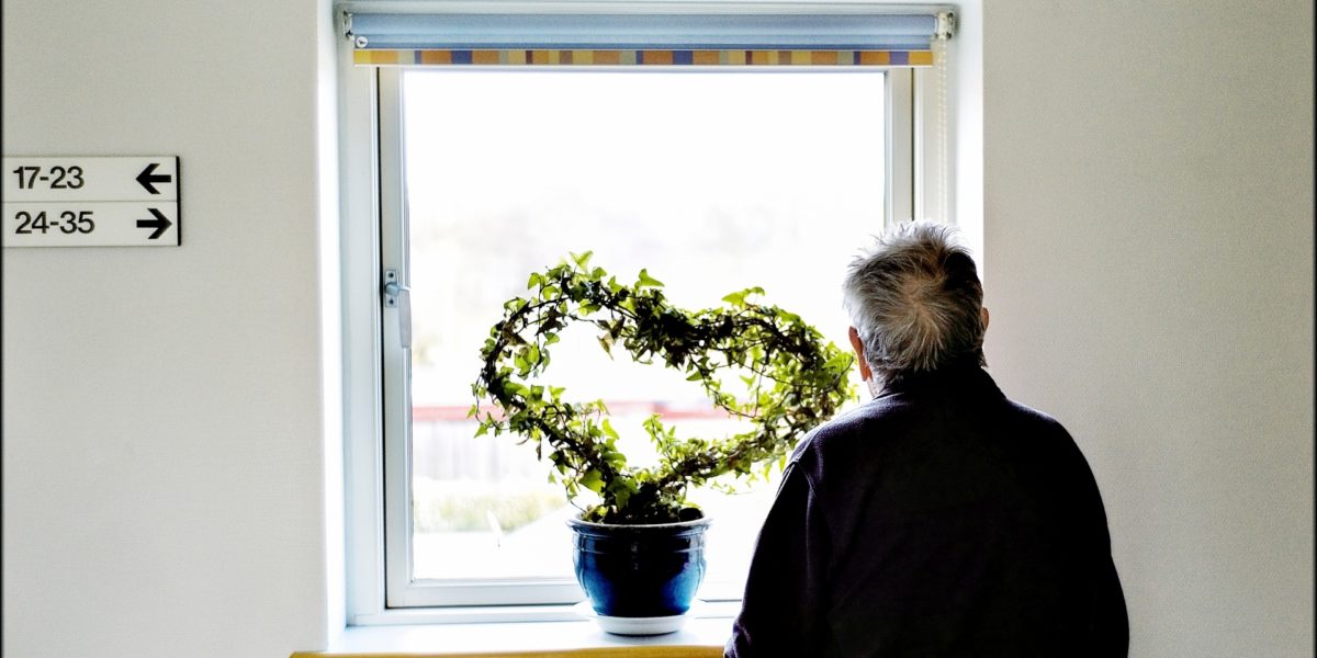 Eldre person står med ryggen til kamera