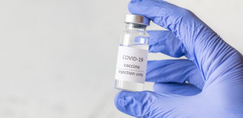 Hånd med blå engangshanske som holder en ampull med teksten Covid-19 vaccine injection only. Foto Hånd med blå engangshanske som holder en ampull med teksten Covid-19 vaccine injection only. Foto