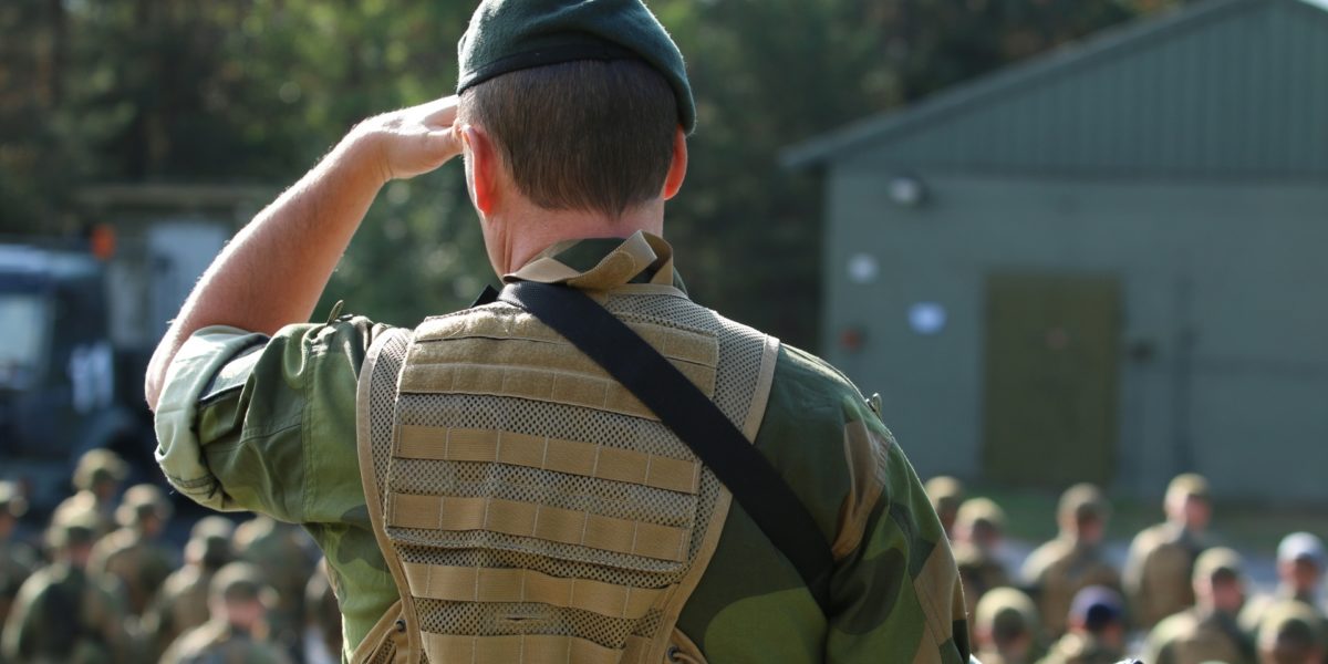 Soldat i giv akt, med ryggen til kamera. Foto.