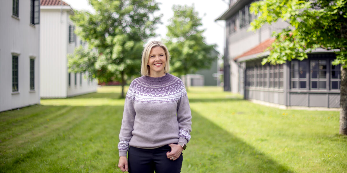 Sylvi Listhaug, smilende i lilla ullgenser. Bak henne grønt gress og grønne trær. Foto. Sylvi Listhaug, smilende i lilla ullgenser. Bak henne grønt gress og grønne trær. Foto.