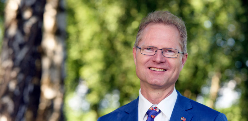 Tor André Johnsen, smilende, uskarpe trær i bakgrunnen. Foto. Tor André Johnsen, smilende, uskarpe trær i bakgrunnen. Foto.
