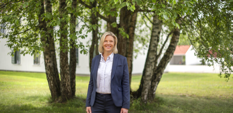 Sylvi Listhaug, smilende ikledd dressjakke. I bakgrunnen grønne trær. Foto. Sylvi Listhaug, smilende ikledd dressjakke. I bakgrunnen grønne trær. Foto.